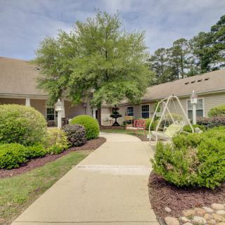 A serene courtyard with a pathway leading through lush gardens and a swing set near a building.