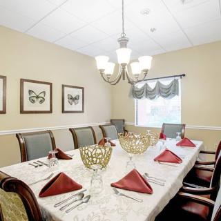 A formal dining room set with a large table, ornate chairs, and decorative butterfly artwork on the walls.