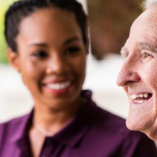 A caregiver and an elderly person sharing a joyful moment.