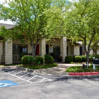 A small building surrounded by trees with a visible parking lot and handicap parking space.