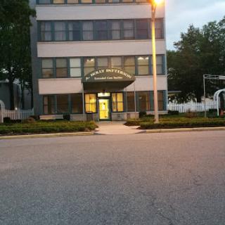 A modern multi-story building captured at dusk, illuminated by street lights.