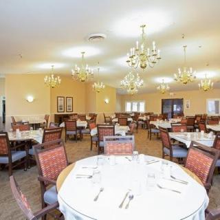 A spacious and elegant dining room with neatly arranged tables and chandeliers.