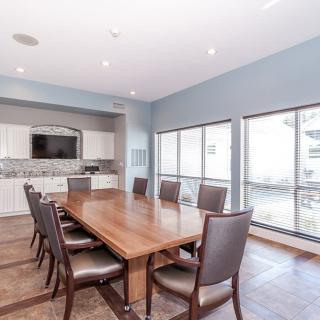 A modern conference room with a large wooden table surrounded by chairs and natural light from large windows.