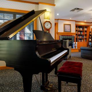 A cozy living room featuring a grand piano and bookshelves.