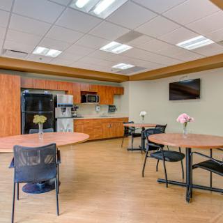 A modern kitchen and dining area featuring wooden cabinetry, round tables, and a cozy atmosphere.