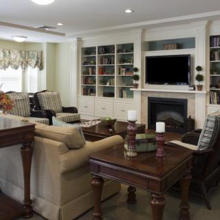 A well-furnished living room featuring a cozy seating area, built-in bookshelves, and a fireplace with a television above.