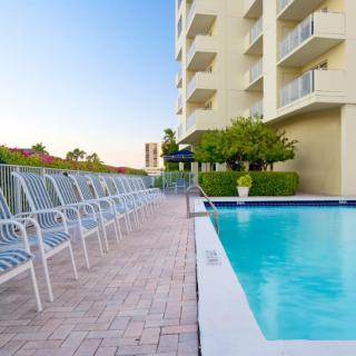 An inviting swimming pool located alongside a hotel, with lounge chairs arranged neatly along the poolside.