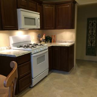 A cozy kitchen featuring dark wood cabinets, a microwave, and a gas stove.