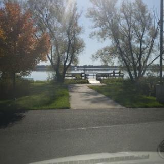 A serene view of a lake with a wooden pier surrounded by trees.