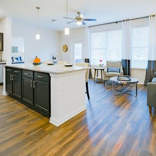 A bright and modern open-concept kitchen and living area featuring hardwood floors and a central island.