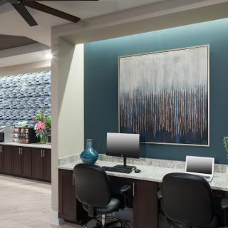 A modern office workspace featuring computers and abstract artwork on the wall.