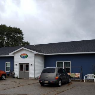 A blue and white building with a parking lot in front, under an overcast sky.