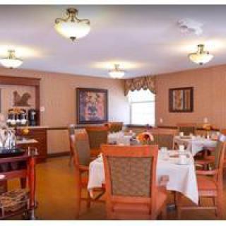 A cozy dining room with neatly arranged tables and chairs, warm lighting, and tasteful decor.