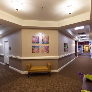 A well-lit hallway featuring colorful artwork and a small bench along the wall.