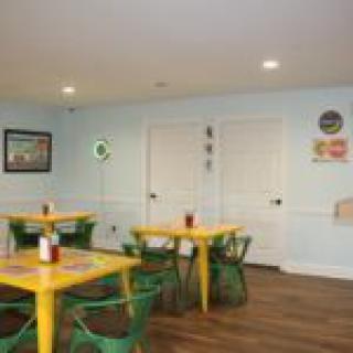 A cozy restaurant dining area with yellow tables and green chairs, complemented by wall decorations.