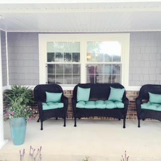 A cozy porch with black chairs and teal cushions, perfect for relaxing outdoors.