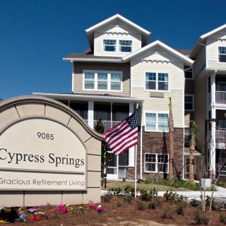 Cypress Springs Gracious Retirement Living building with an American flag.