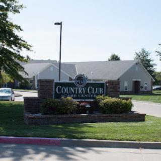 A sunny view of the Country Club entrance, showcasing the sign and surrounding landscape.