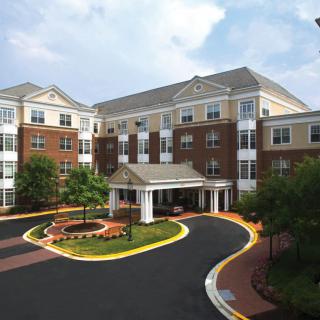 A modern residential building with a landscaped entrance and circular drive.