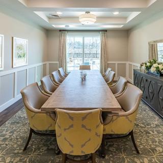 A modern dining room or meeting space featuring an elegant conference table surrounded by upholstered chairs.