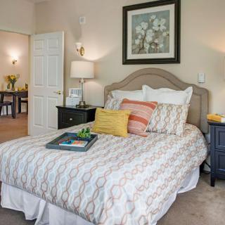 A cozy bedroom with a neatly made bed, decorative pillows, and stylish artwork on the wall.