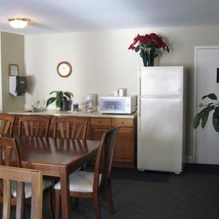 A cozy kitchen and dining area with a wooden table and chairs, a refrigerator, and decorative plants.