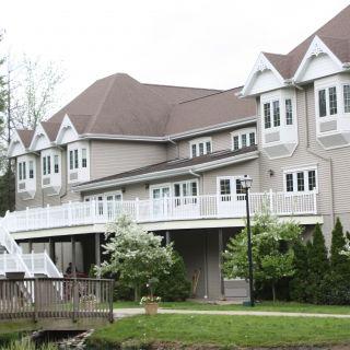 A large residential house with multiple windows and balconies surrounded by trees.