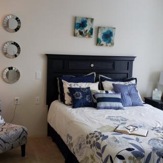 A well-decorated bedroom with a dark headboard, floral bedding, and coordinating wall art and mirrors.
