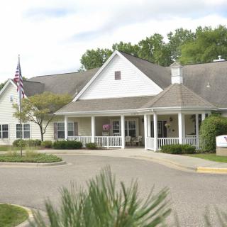 A suburban residential building with an American flag, surrounded by trees and a driveway.