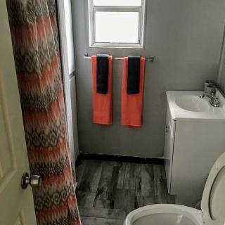 A modern bathroom with orange and black towels, a shower curtain, toilet, and sink.