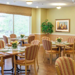 A cozy dining area with neatly arranged tables and chairs, decorated with plants and artwork.