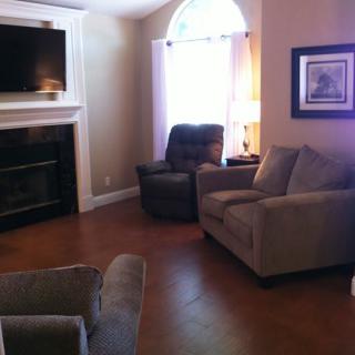 A cozy living room with sofas, armchairs, and a fireplace, featuring a television mounted above.