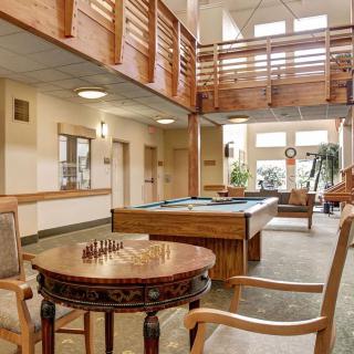 A well-lit recreational area featuring a pool table and a chess board with comfortable seating and wooden accents.