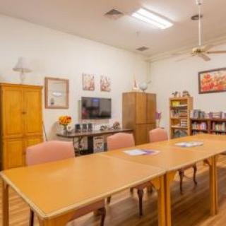 A cozy conference room equipped with a long table, chairs, television, and bookshelf.