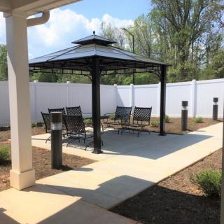 A serene outdoor patio area featuring a gazebo with seating and a surrounding garden.