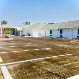 A view of a building with an adjoining parking lot under a clear sky.