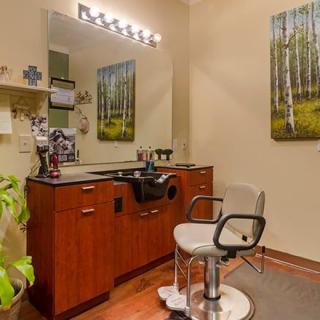A cozy hair salon setup featuring a styling chair, vanity with a mirror, and decorative elements.