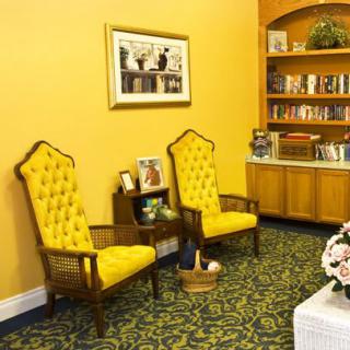 A cozy room featuring yellow upholstered chairs, a bookshelf, and decorative elements.
