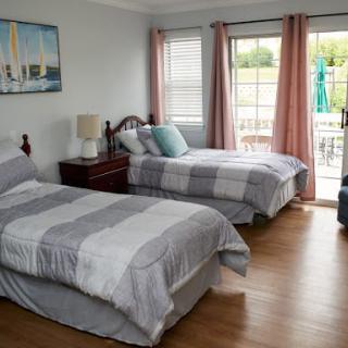 A cozy bedroom with twin beds, soft curtains, and a view outside.