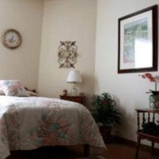A cozy bedroom with a bed, nightstand, lamp, and decorative elements.