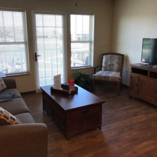 A cozy living room with a sofa, chair, coffee table, and television near large windows.