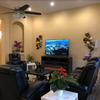 A modern living room with leather seating and a large TV, complemented by decorative plants and wall art.