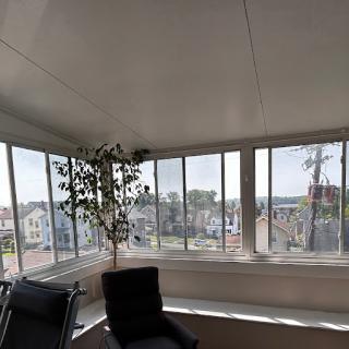 A bright sunroom with large windows offering a view of the city.