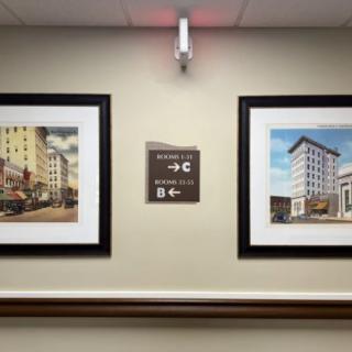 A hallway with framed artwork and a directional sign on the wall.