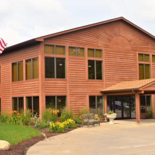 A wooden office building with a flag and landscaped surroundings.