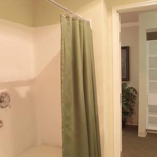 A view of a bathroom featuring a shower with a green curtain.