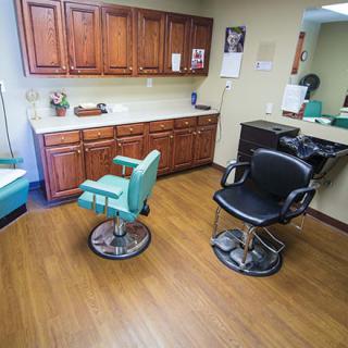 A well-organized hair salon with two styling chairs, cabinets, and a large mirror.