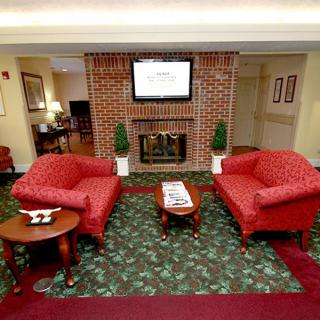 A cozy living room with red sofas, a fireplace, and a wall-mounted television.