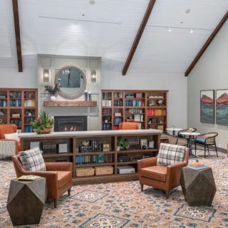 A cozy library interior with comfortable seating, bookshelves, and a fireplace.