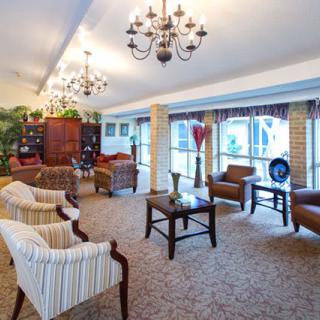 A spacious living room with elegant chandeliers, comfortable seating, and large windows.